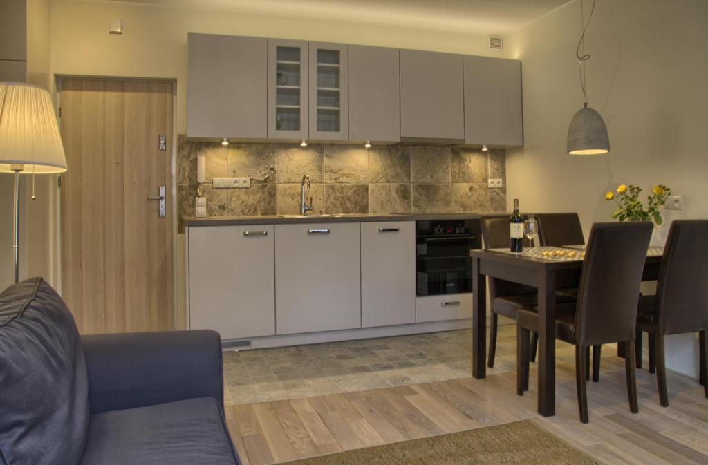 a kitchen with white cabinets and a table with chairs at Gdańsk deluxe Apartments Gdansk in Gdańsk