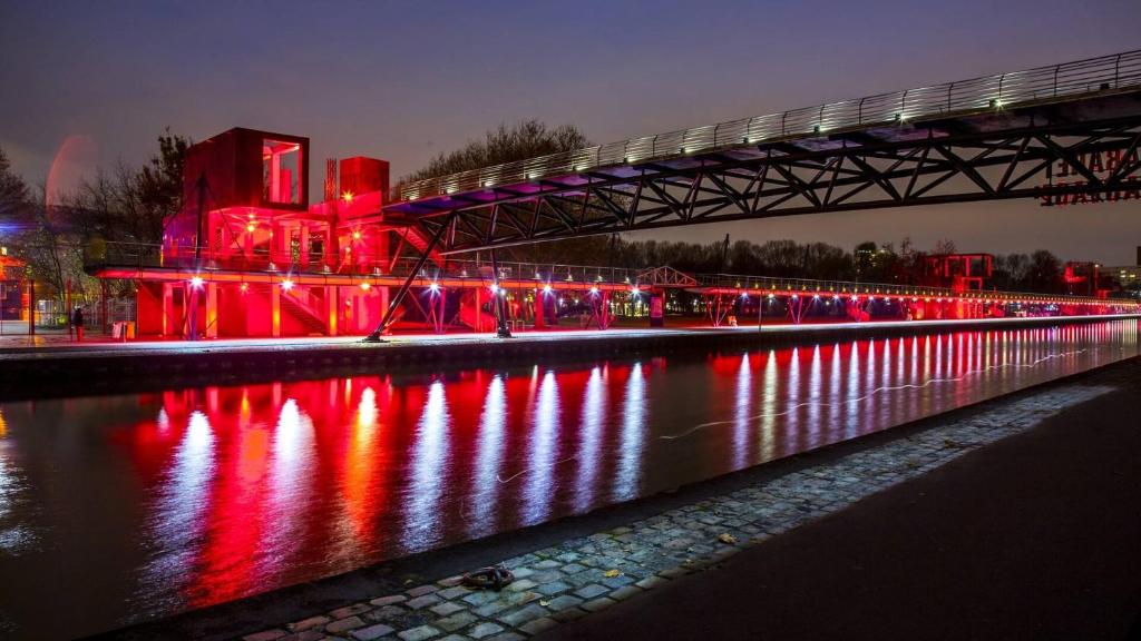 a bridge with red lights over a river at night at Studio de charme in Pantin