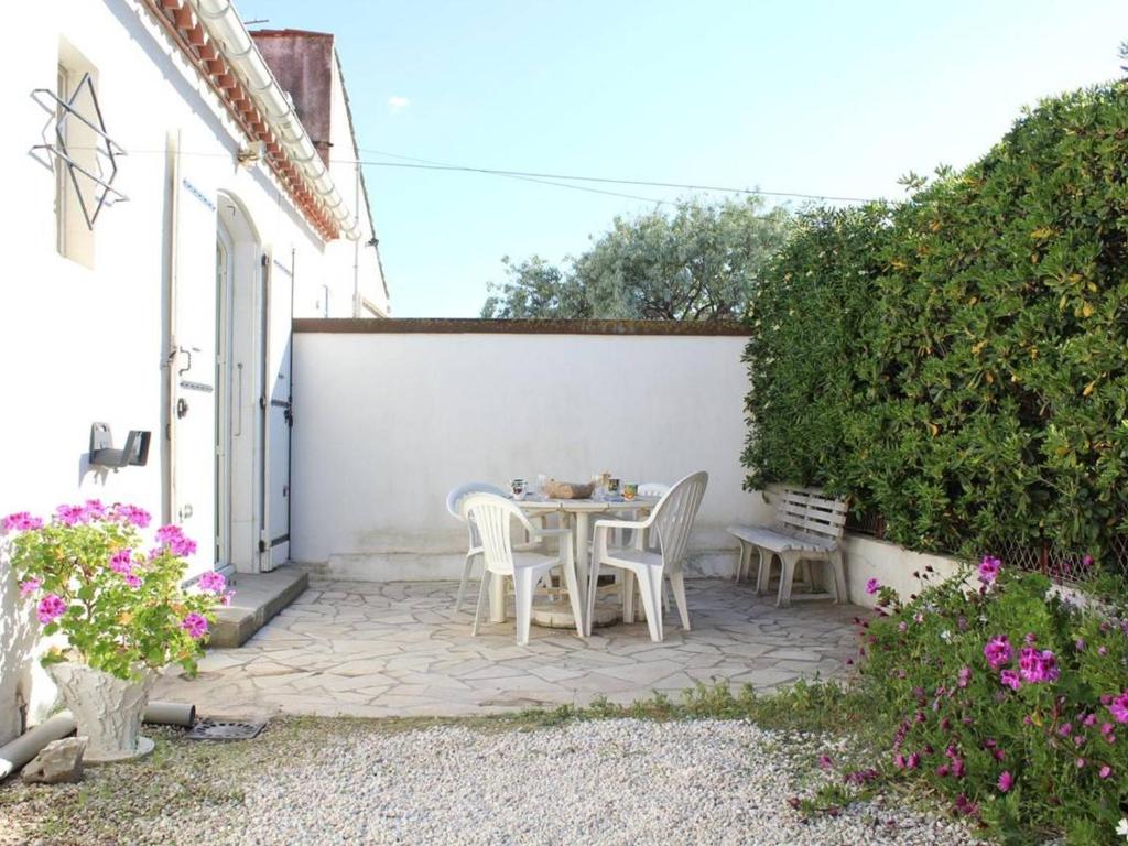 d'une terrasse avec une table et des chaises à côté d'un mur blanc. dans l'établissement Maison familiale 3 pièces, terrasse, proche plage, parking - Port-la-Nouvelle - FR-1-229C-688, à Port-la-Nouvelle