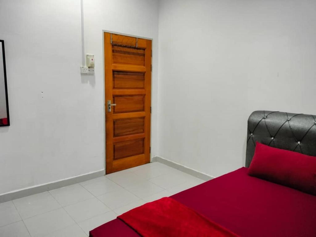 Cette chambre comprend un lit avec un oreiller rouge et une porte. dans l'établissement KUALA TERENGGANU GUESTHOUSE-FREE WIFI-NEAR NASI DAGANG ATAS ToL-UNIT A-1 BILIK AIRCOND 2 BILIK KIPAS, à Kuala Terengganu