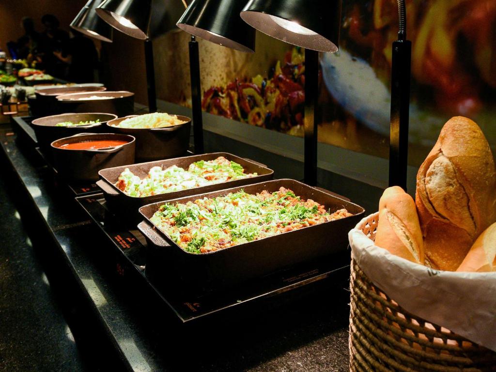 a buffet line with trays of pizzas and bread at ibis Guarulhos Aeroporto in Guarulhos