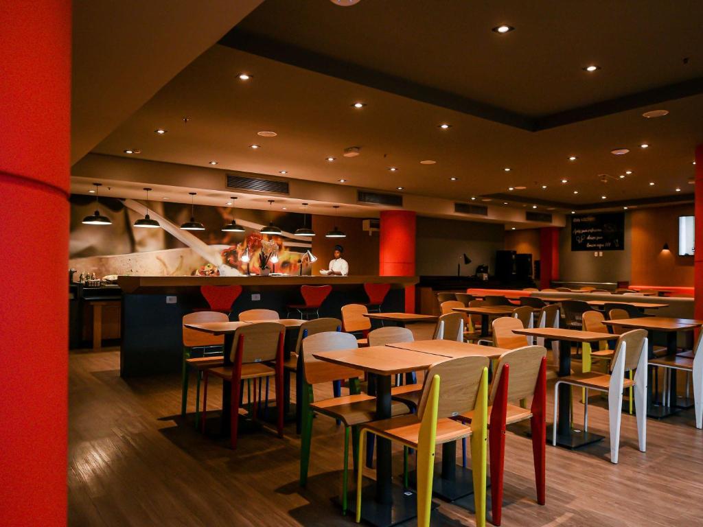 a restaurant with tables and chairs and a bar at ibis Guarulhos Aeroporto in Guarulhos