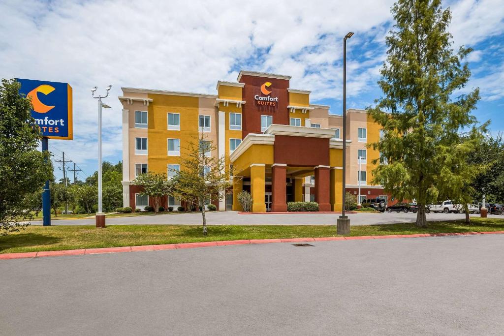 un grand bâtiment jaune avec un panneau devant lui dans l'établissement Comfort Suites Denham Springs, à Denham Springs
