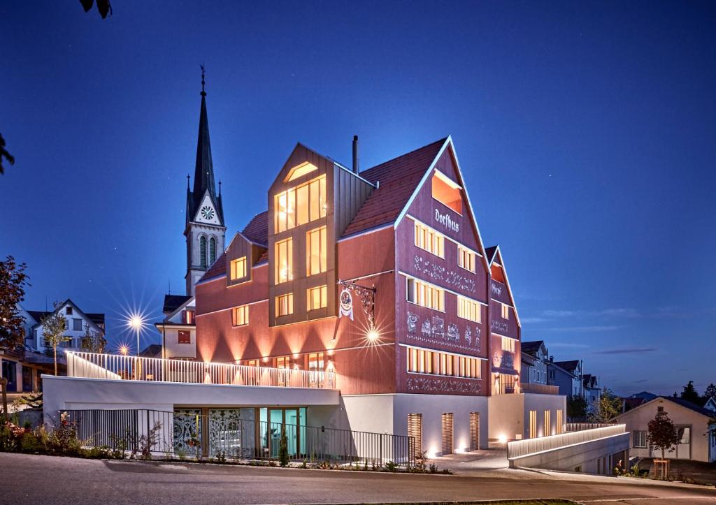 a large building with a church in the background at Dorfhus Gupf in Rehetobel