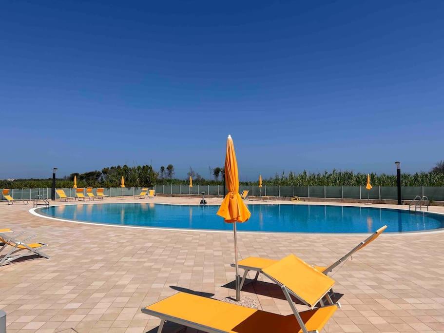 una sombrilla amarilla y sillas junto a la piscina en Casa vacanze, en Campomarino