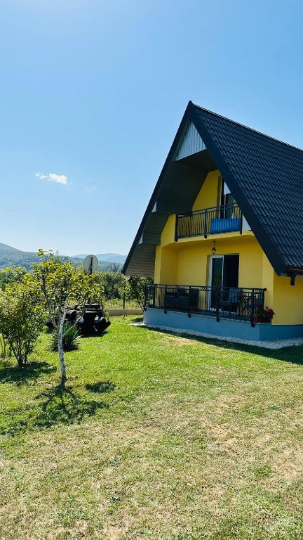 a yellow house with a black roof and a yard at B&B Hills Bihać in Bihać