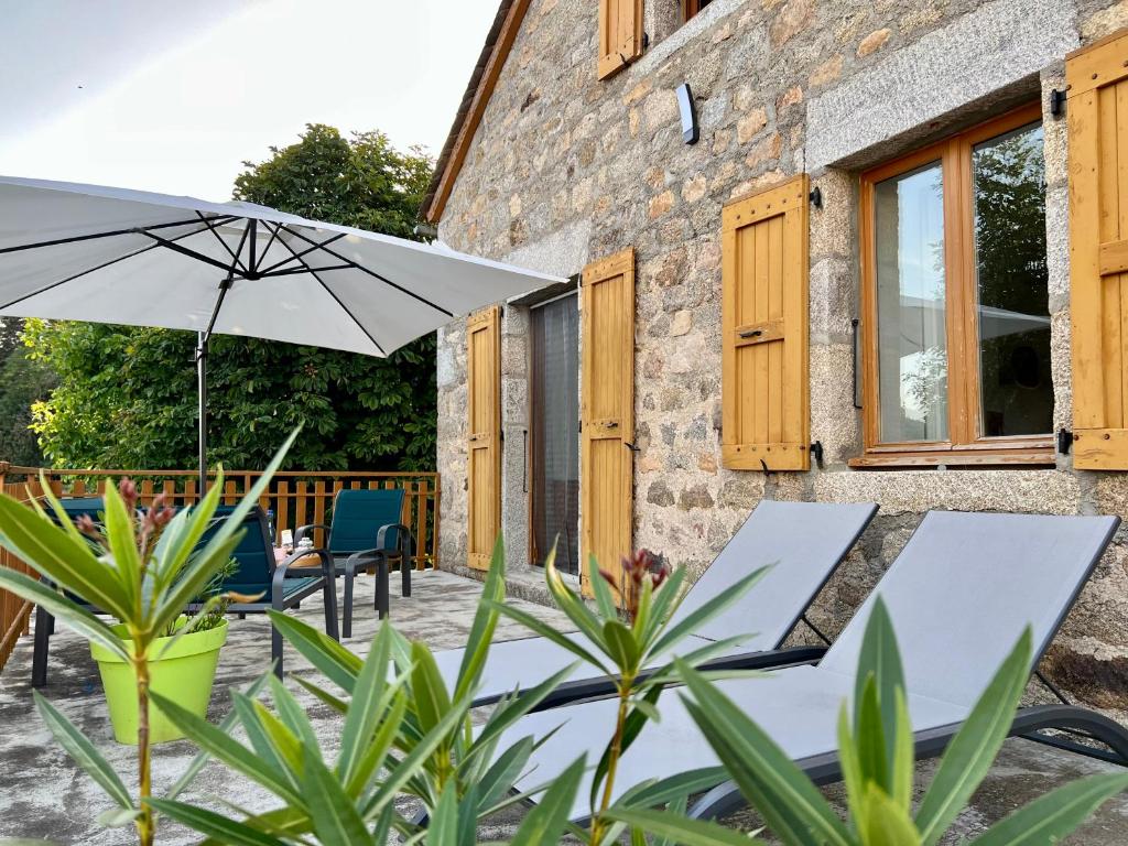 un patio con 2 sillas y una sombrilla en Chez Marie, en Albaret-Sainte-Marie
