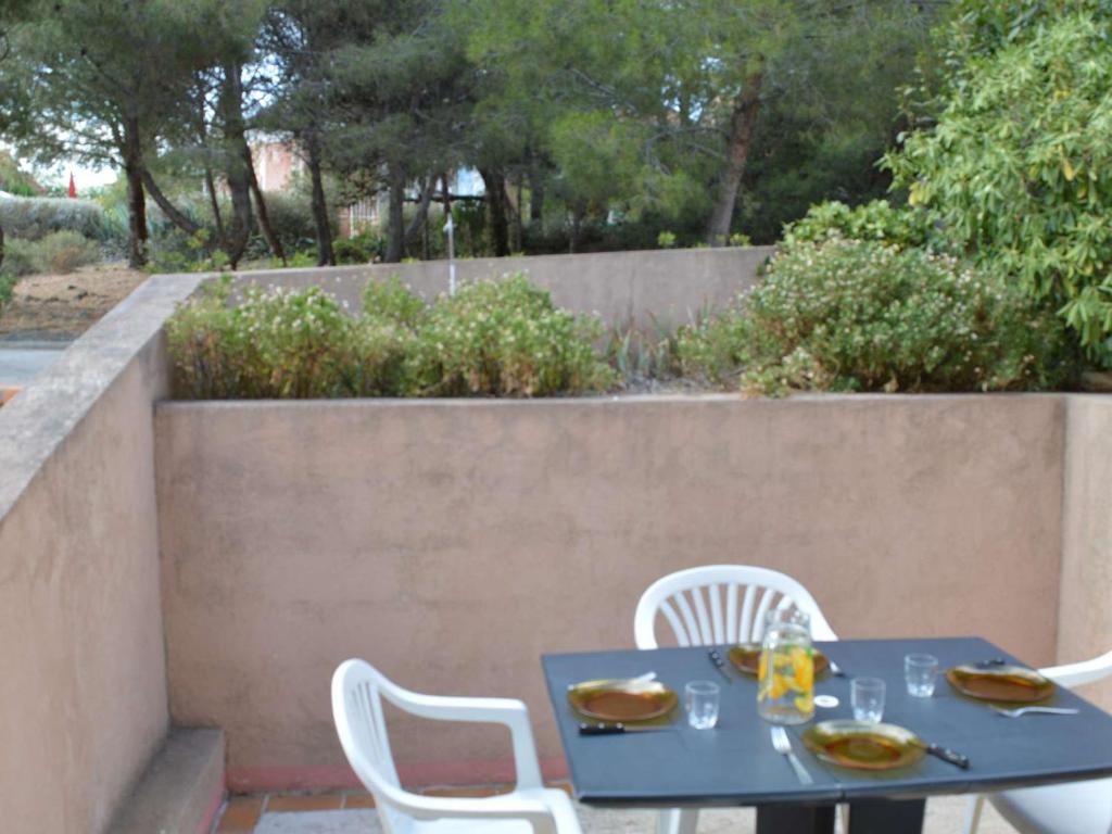 - une table bleue et des chaises blanches sur la terrasse dans l'établissement Studio Cabine avec Terrasse, Piscine et Parking Privé, 4 Couchages à Narbonne Plage - FR-1-229B-62, à Narbonne