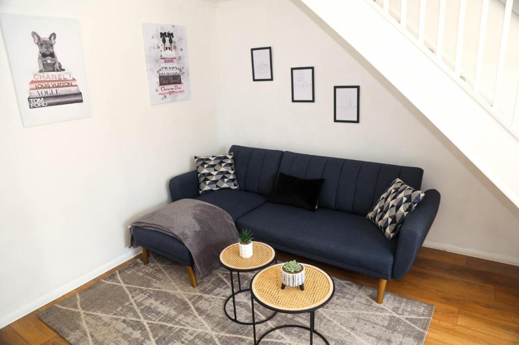 a living room with a blue couch and two tables at Luxe Cosy&Spacious 2 Bed House - Super Fast Wi-Fi & Private Parking Near GLO Airport & Cheltenham Racecourse in Churchdown