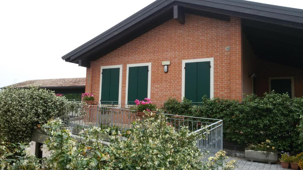 a red brick house with green doors and plants at Albergo del Po in Viadana