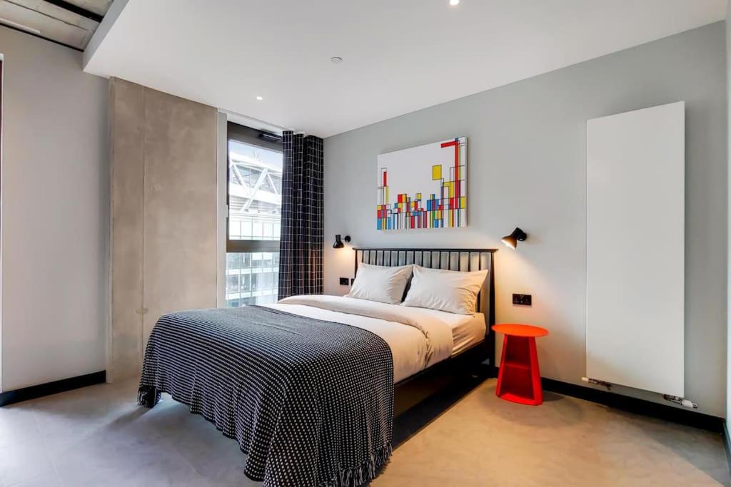 a bedroom with a bed and a red stool at Wembley Park Modern Flat in London