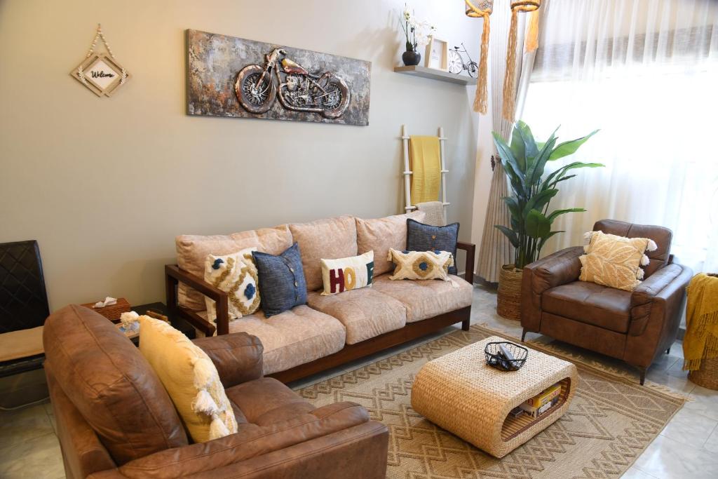 uma sala de estar com um sofá e cadeiras castanhos em Gamaleo Apartment Namulanda em Namulanda