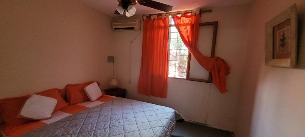 a bedroom with a bed and a window with orange curtains at OASIS II Las Moras, con cochera y jardin in La Rioja