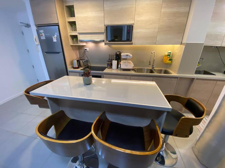 a kitchen with a counter with chairs around it at Cómodo departamento en Caldera, con piscina. in Caldera