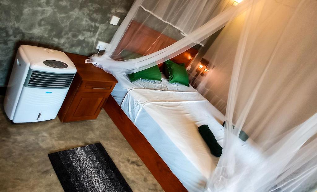 um quarto com 2 camas com cortinas e uma secretária em Rain Forest Star em Deniyaya