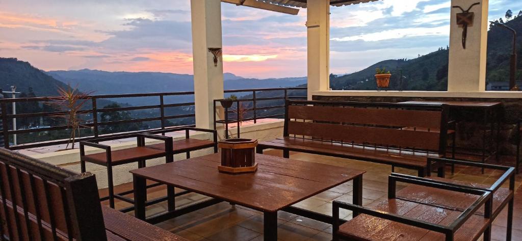 a balcony with tables and chairs and a view of mountains at Thesula Valley in Kodaikānāl