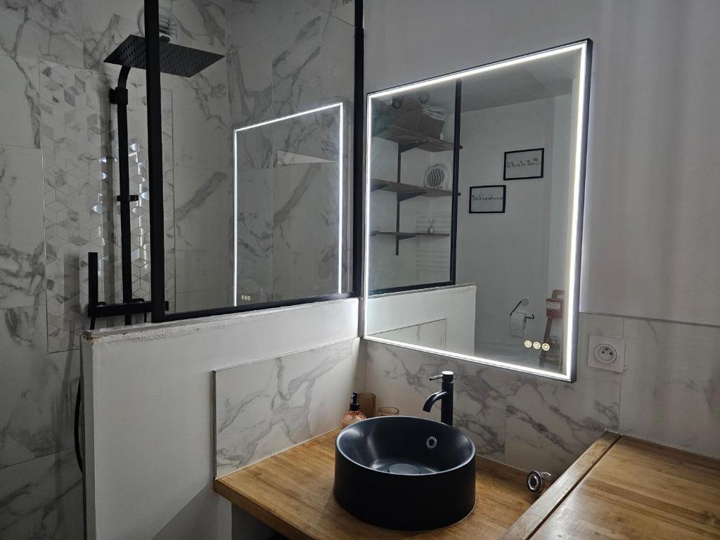 ein Bad mit einem schwarzen Waschbecken und einem Spiegel in der Unterkunft Cosy T2 entre terre et mer in Montpellier