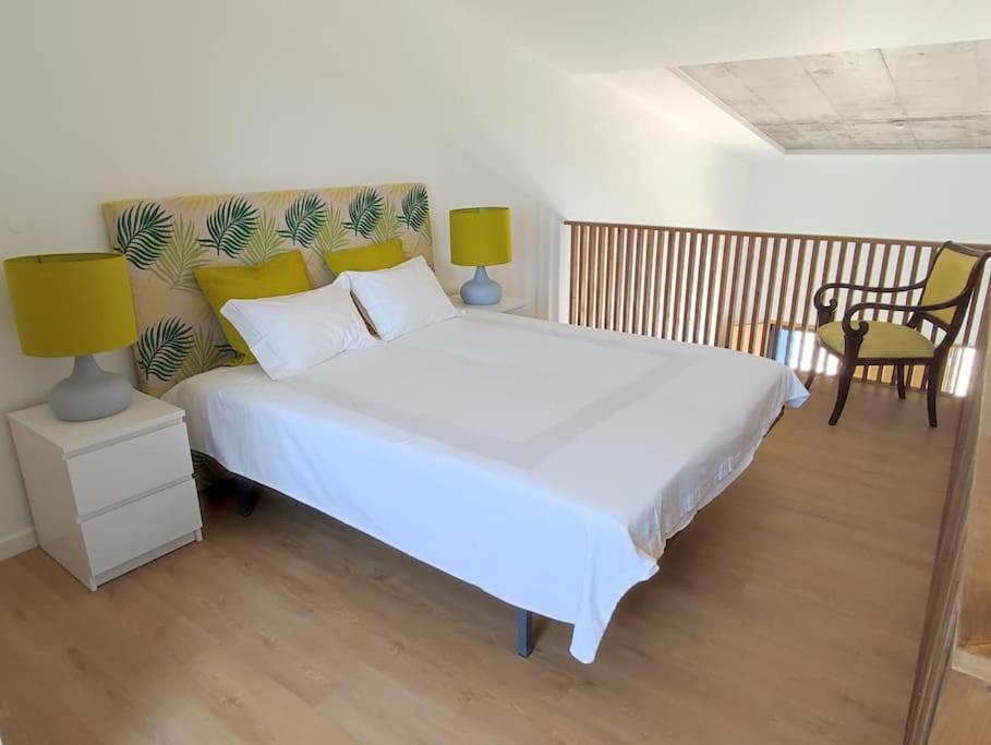 una camera da letto con un grande letto bianco con cuscini gialli di Ocean & Countryside Apartments a Encarnação