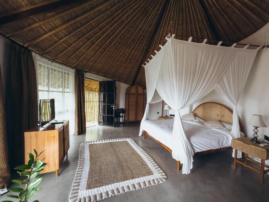 a bedroom with a bed with a mosquito net at Hillstone U Villa in Uluwatu