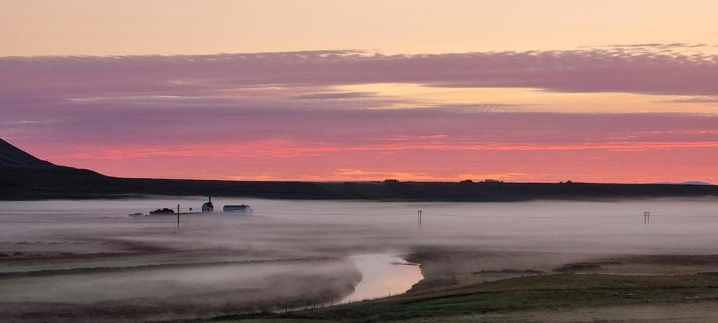 um rio enevoado com um pôr-do-sol ao fundo em Gil guesthouse em Búðardalur