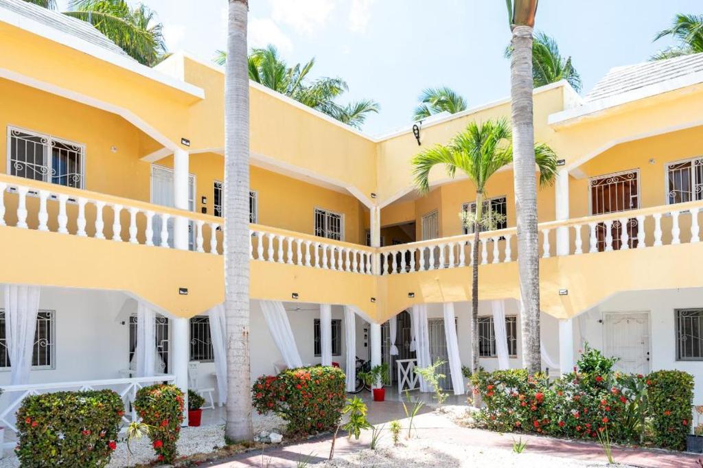 un edificio amarillo con palmeras y flores en Hermosa Suites #2 in the heart of PUNTA CANA en Punta Cana