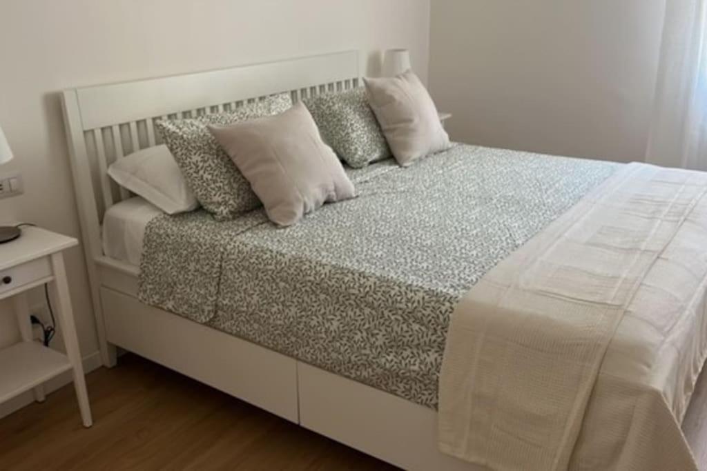 een wit bed met kussens in een slaapkamer bij Pelusia apartment in Modena