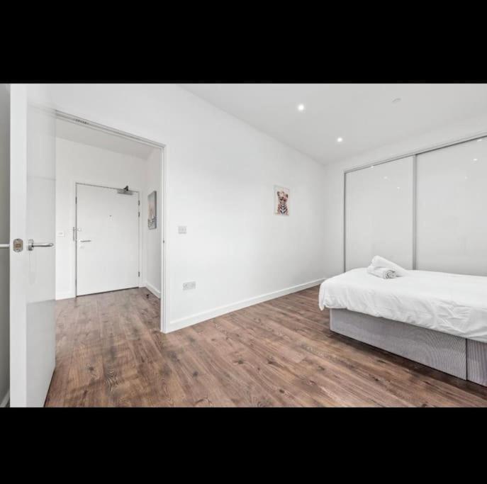 a white bedroom with a bed and a large mirror at Delta Haven 1 BR Flat 15Mins to LondonBridge DP272 in Croydon