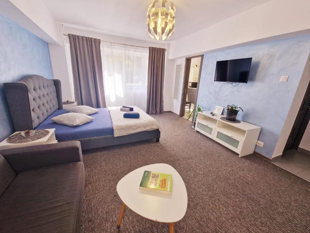 Habitación de hotel con cama, sofá y mesa en Marcos Apartments - self check-in, en Reşiţa