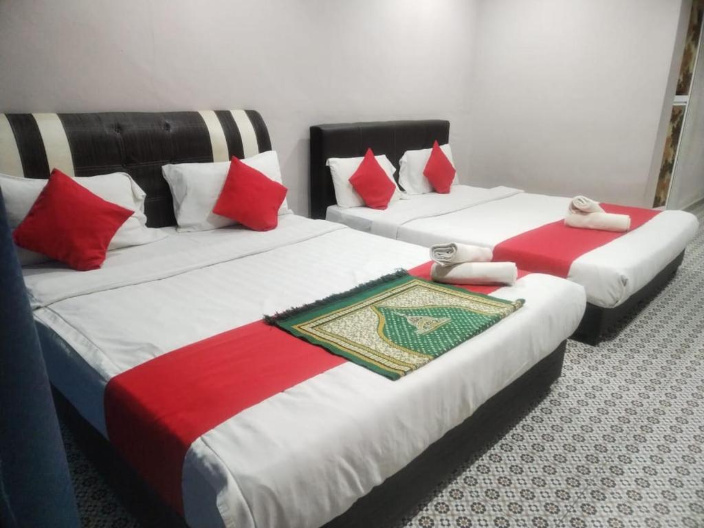 2 letti con cuscini rossi e bianchi in una stanza di Ar Rayyan Hotel a Tanah Rata