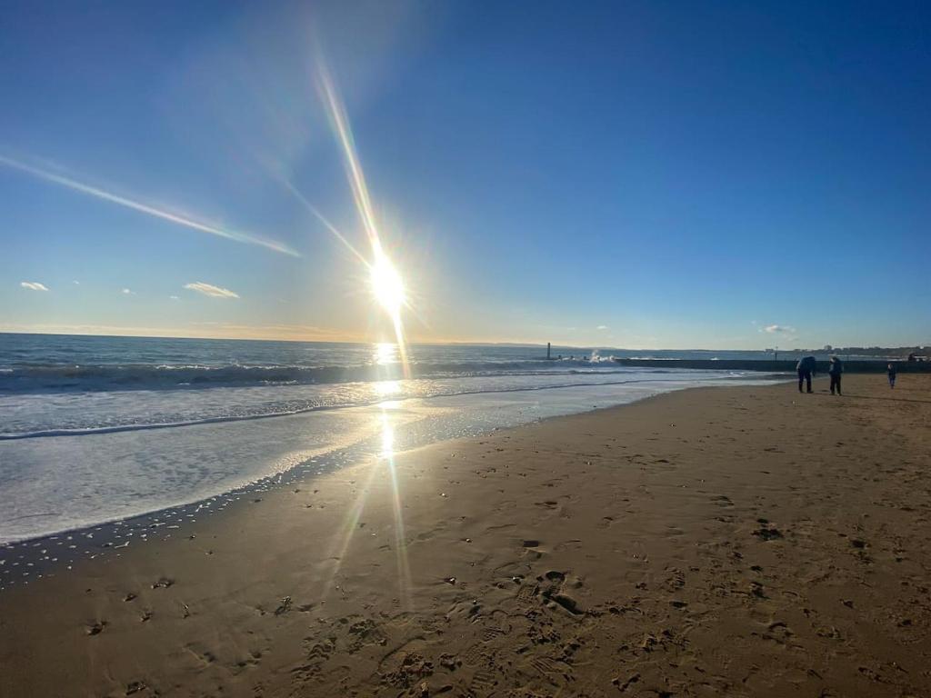 una spiaggia con il sole che splende sulla sabbia di Hathaway Beach House a Southbourne