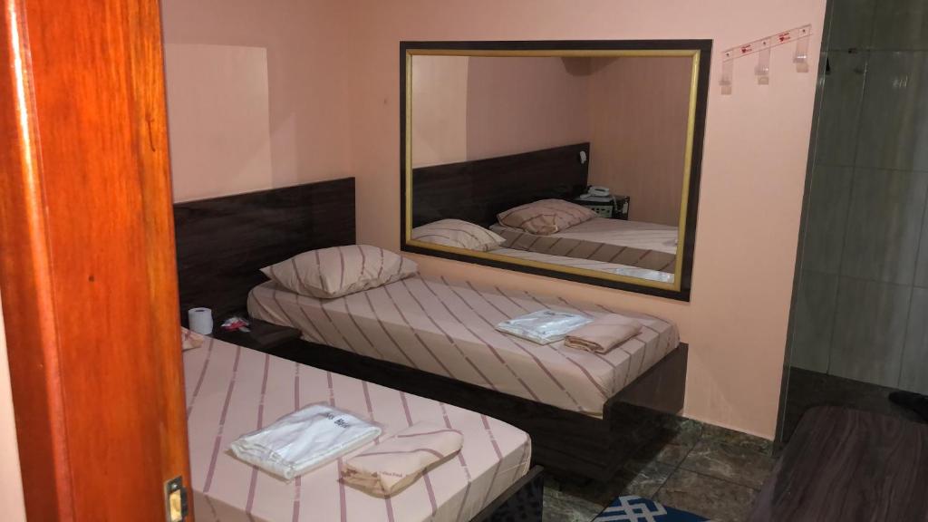 two beds in a room with a mirror at Trilhos Hotel in Sao Paulo