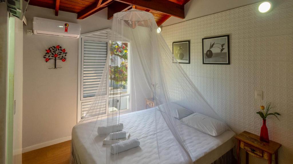 a bedroom with a canopy bed with a window at Guarujá Hostel in Guarujá