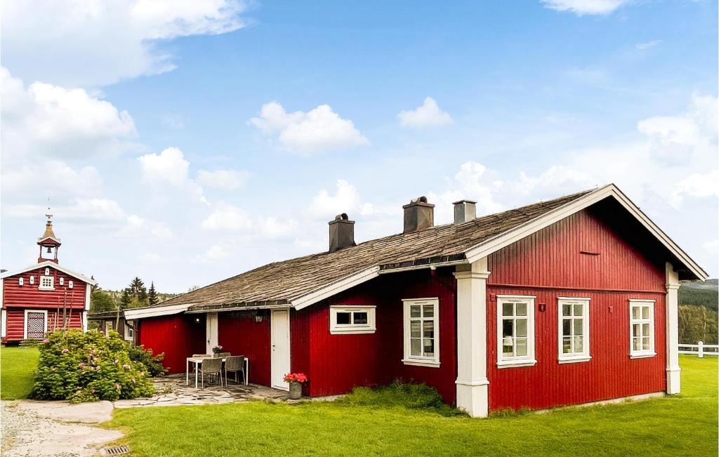 una casa roja con una iglesia al fondo en Lovely Home In Koppang With Kitchen en Koppang