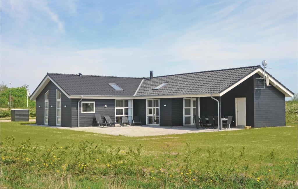 una casa negra con un campo de hierba delante de ella en Pet Friendly Home In Skjern With Kitchen, en Stavning