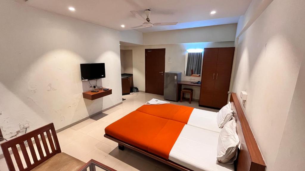 a bedroom with a bed and a television in it at Hotel Sumanchandra Suites in Nashik