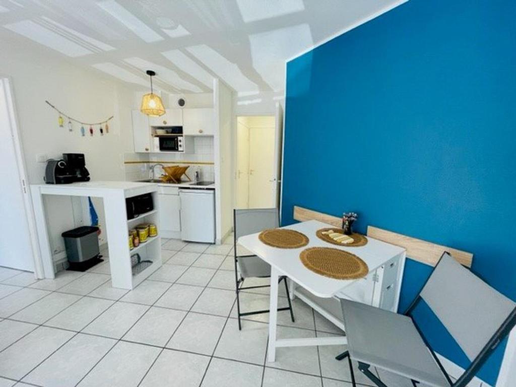 a kitchen with a white table and a blue wall at Appartement Quiberon, 2 pièces, 4 personnes - FR-1-478-259 in Quiberon