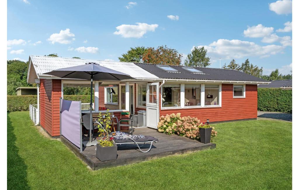 una pequeña casa roja con un paraguas en un patio en Stunning Home In Haderslev With Kitchen, en Diernæs