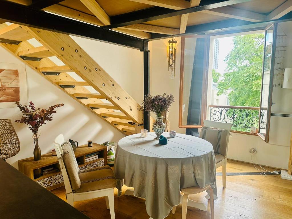 a dining room with a table and a large window at Le Cocon Parisien in Paris