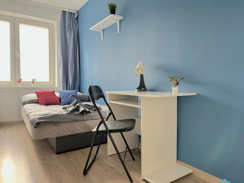 a bedroom with a bed with a desk and a desk chair at Colourful Room in Gdańsk
