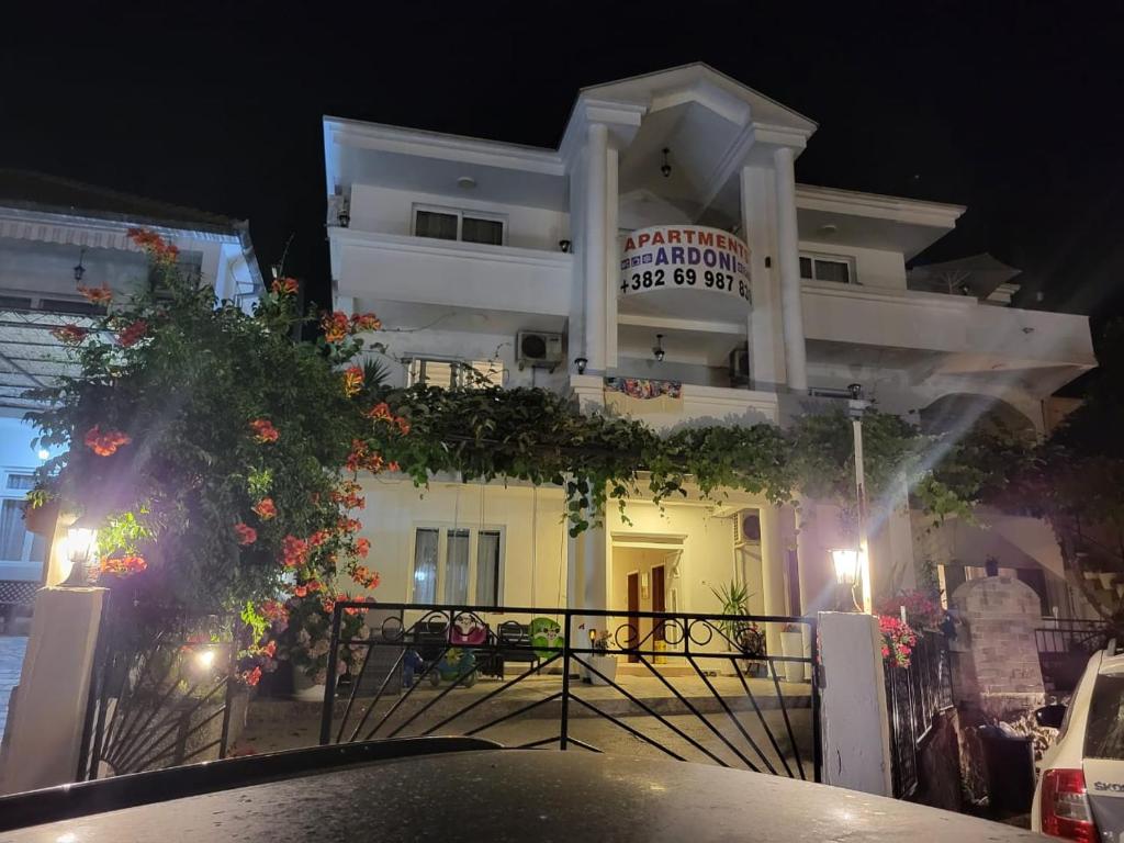 Ein weißes Gebäude mit einem Schild in der Nacht. in der Unterkunft Apartments Ardoni in Ulcinj