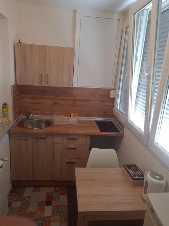 a kitchen with wooden cabinets and a sink and two windows at Kineski zid in Zenica