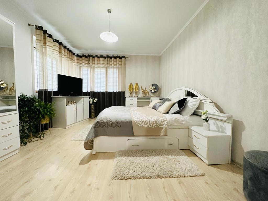 sypialnia z białym łóżkiem i telewizorem w obiekcie Flamingo House w mieście Reghin