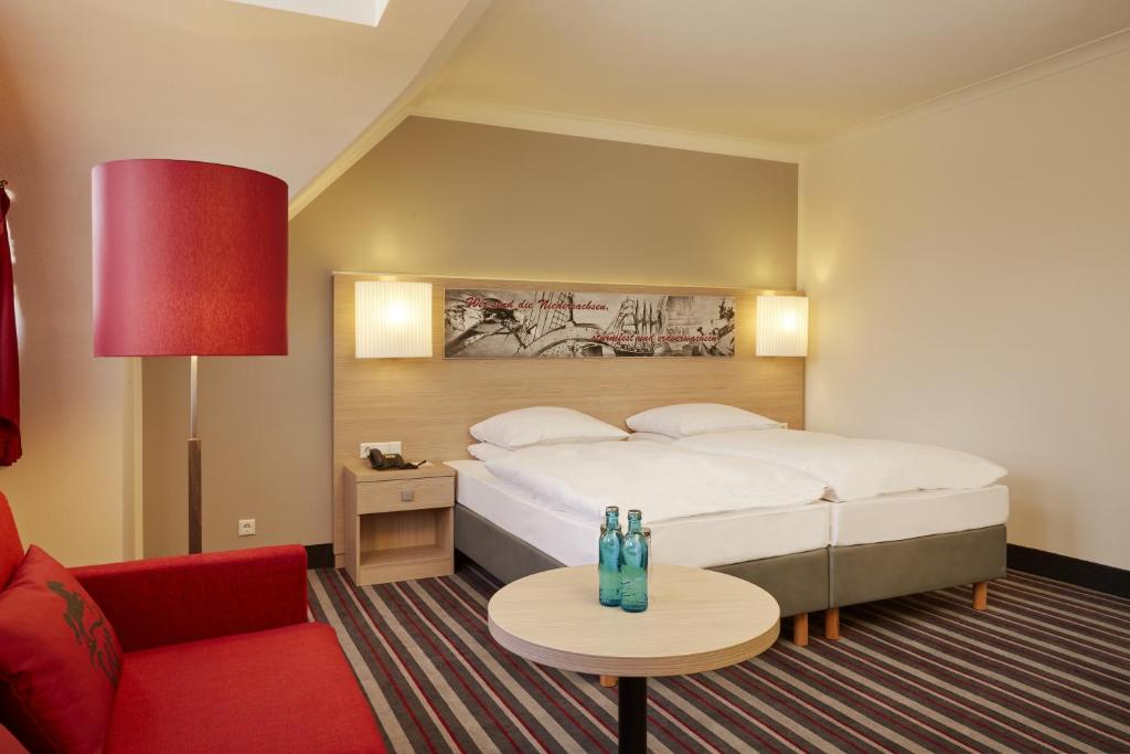 a hotel room with a bed and a red couch at H+ Hotel Stade Herzog Widukind in Stade