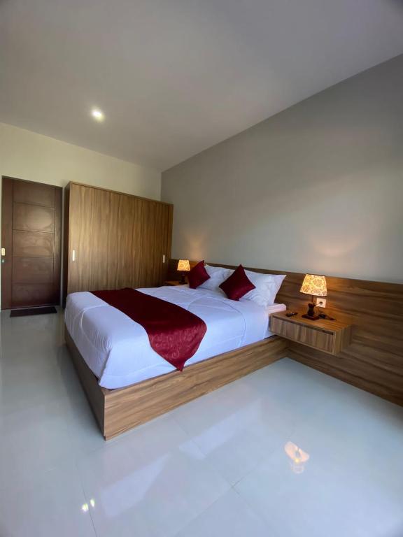 a bedroom with a large bed with a red blanket at Pondok Puspa Sumekar in Seminyak
