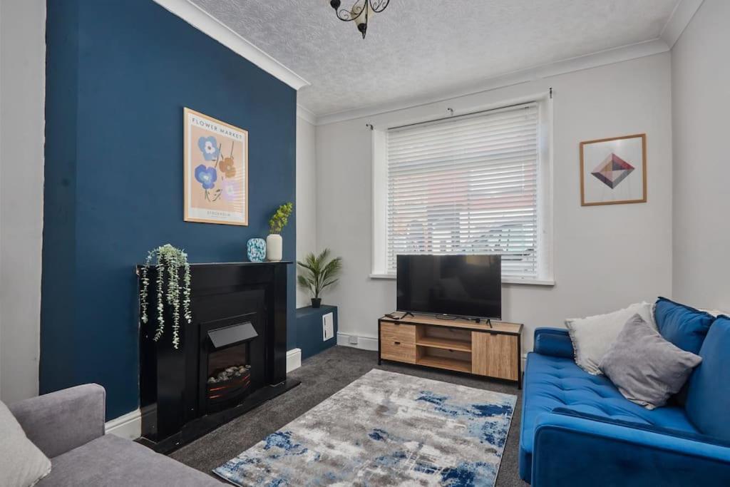 a living room with a blue couch and a tv at Stylish Comfortable Home With Parking in Redcar