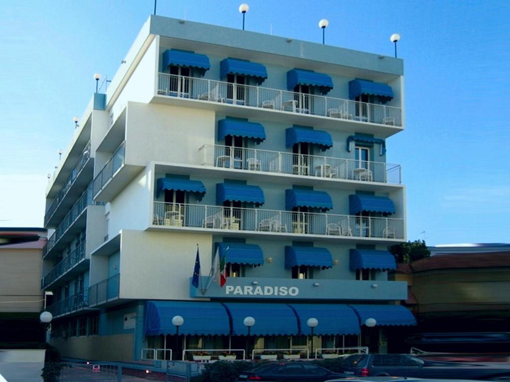 un edificio alto con toldos azules. en Hotel Paradiso, en Senigallia