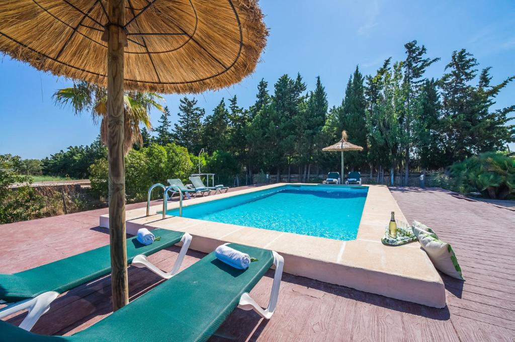 een zwembad met 2 stoelen en een parasol bij Ideal Property Mallorca - Rotes in El Port