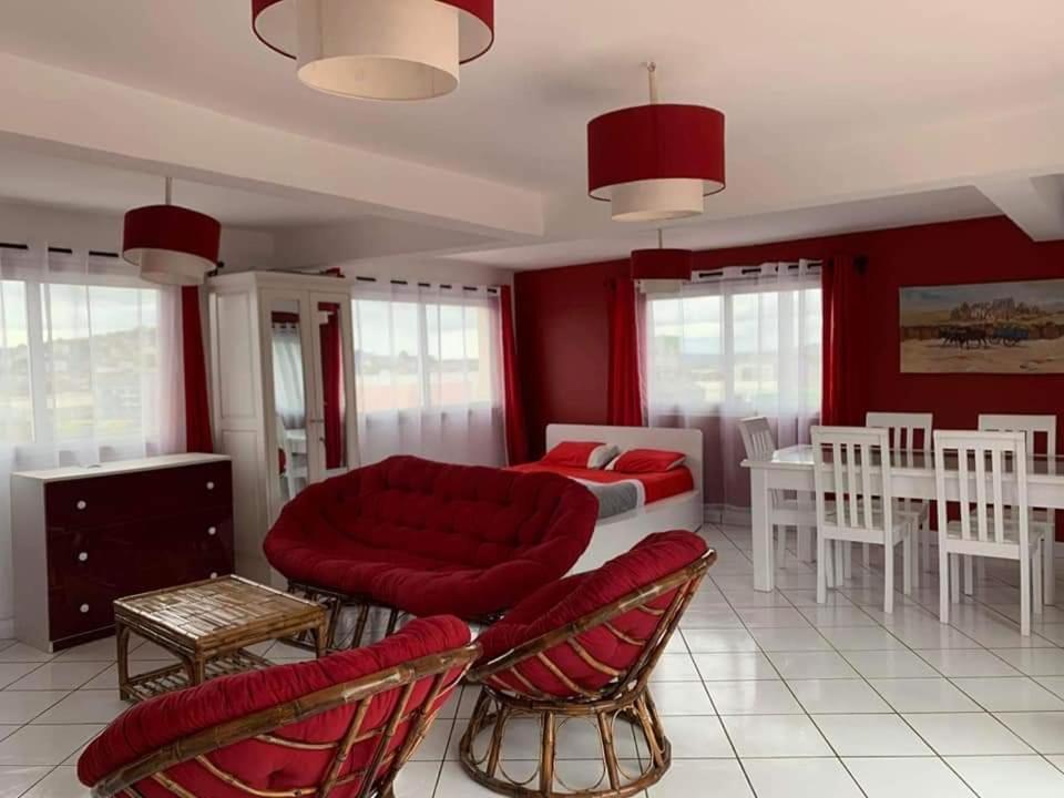 ein Wohnzimmer mit roten Wänden sowie einem Bett und Stühlen in der Unterkunft Appartements Andrian Location in Antananarivo