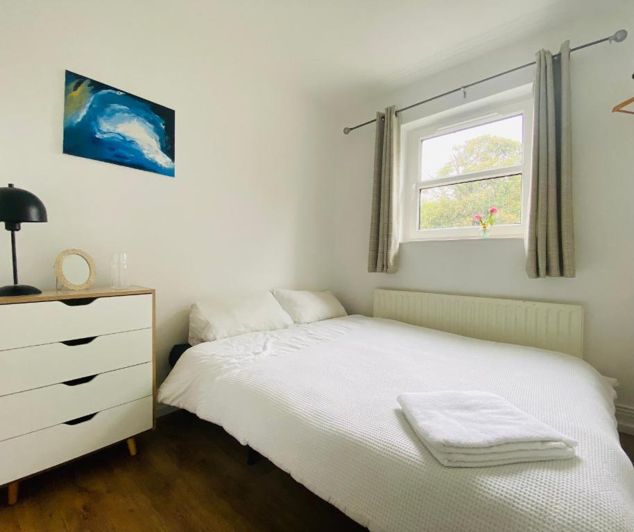 1 dormitorio con cama blanca y ventana en Yellow door cottage en Moville