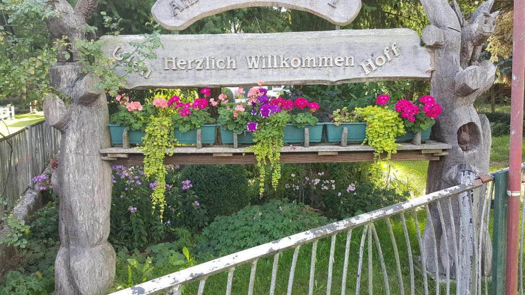a wooden sign with flowers in a garden at Naturnahe Ferienwohnung 